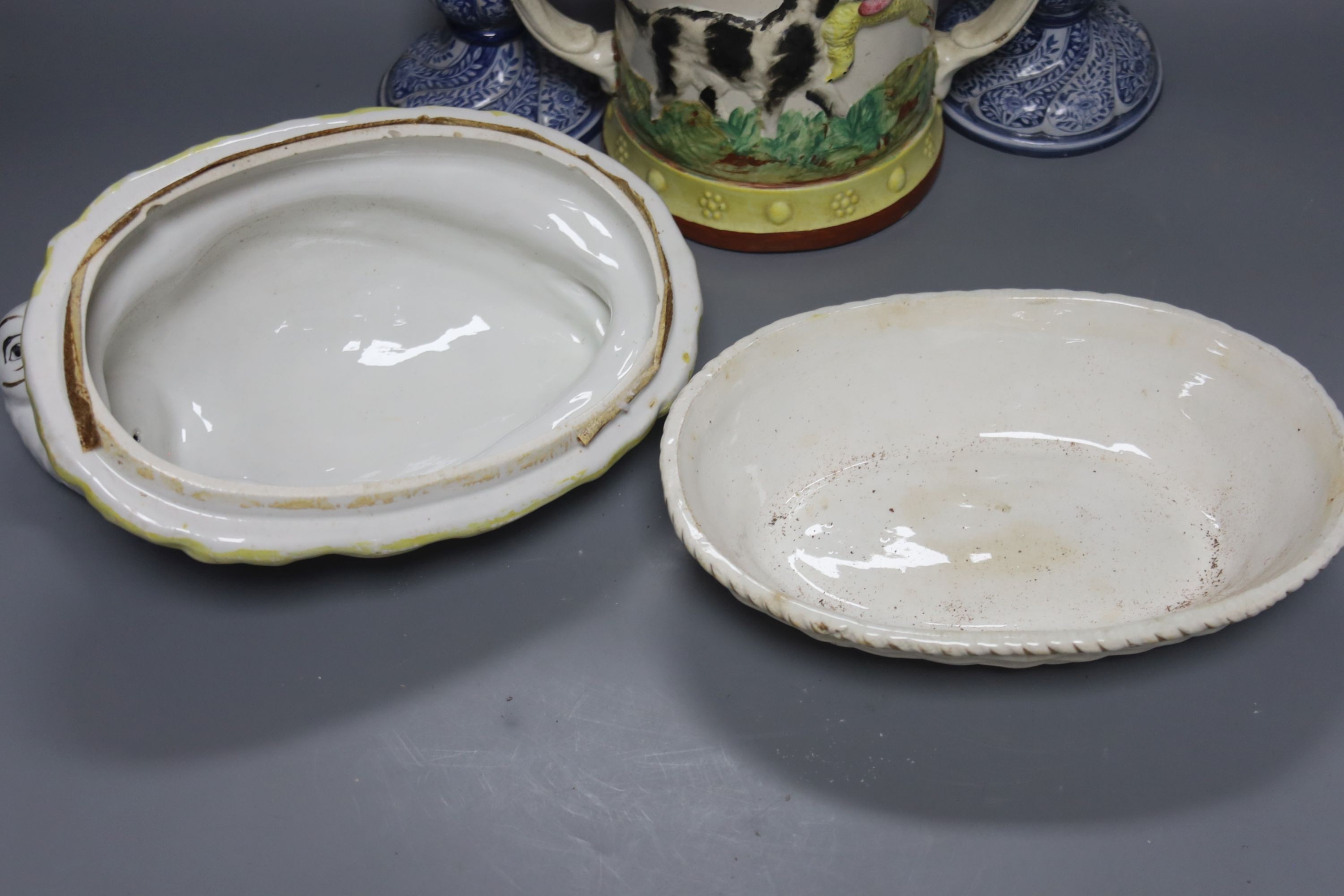 A Staffordshire pottery ‘duck’ tureen and cover, 23cm, a pair of faience candlesticks, Staffordshire figures of dogs, sheep and a zebra and a two handled loving mug